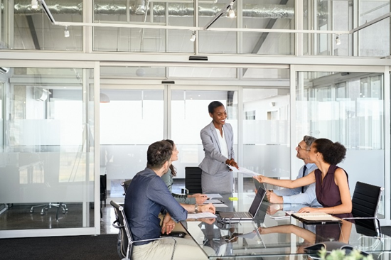 team meeting in an office at a table with a leader standing