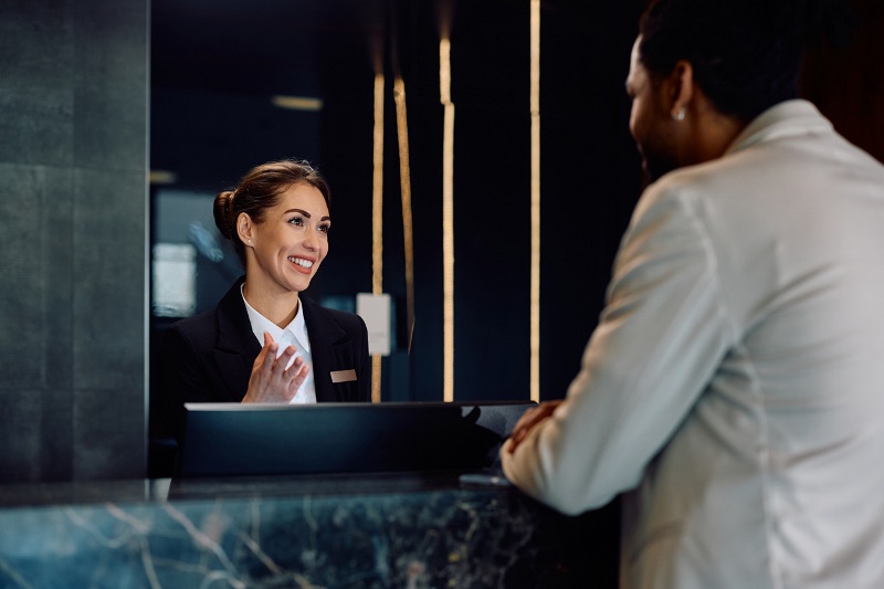 Customer service team member checking guest in at hotel lobby